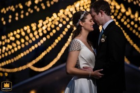 A couple shares an embrace at night in Arabelle Square, Vail, Colorado, with strings of market lights illuminating the background.